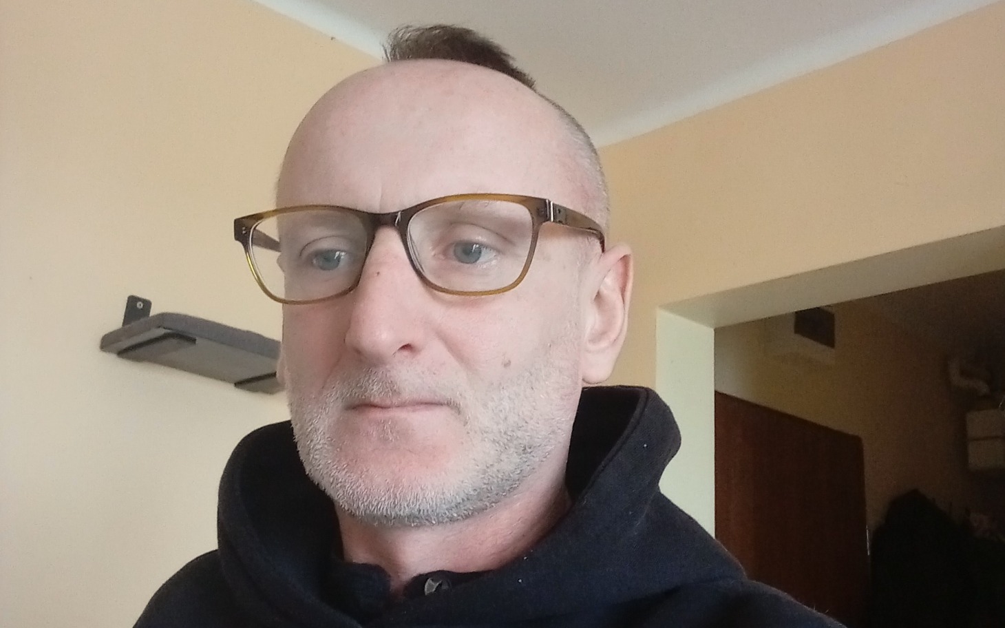 
        Mężczyzna w okularach, patrzący w kamerę.
    