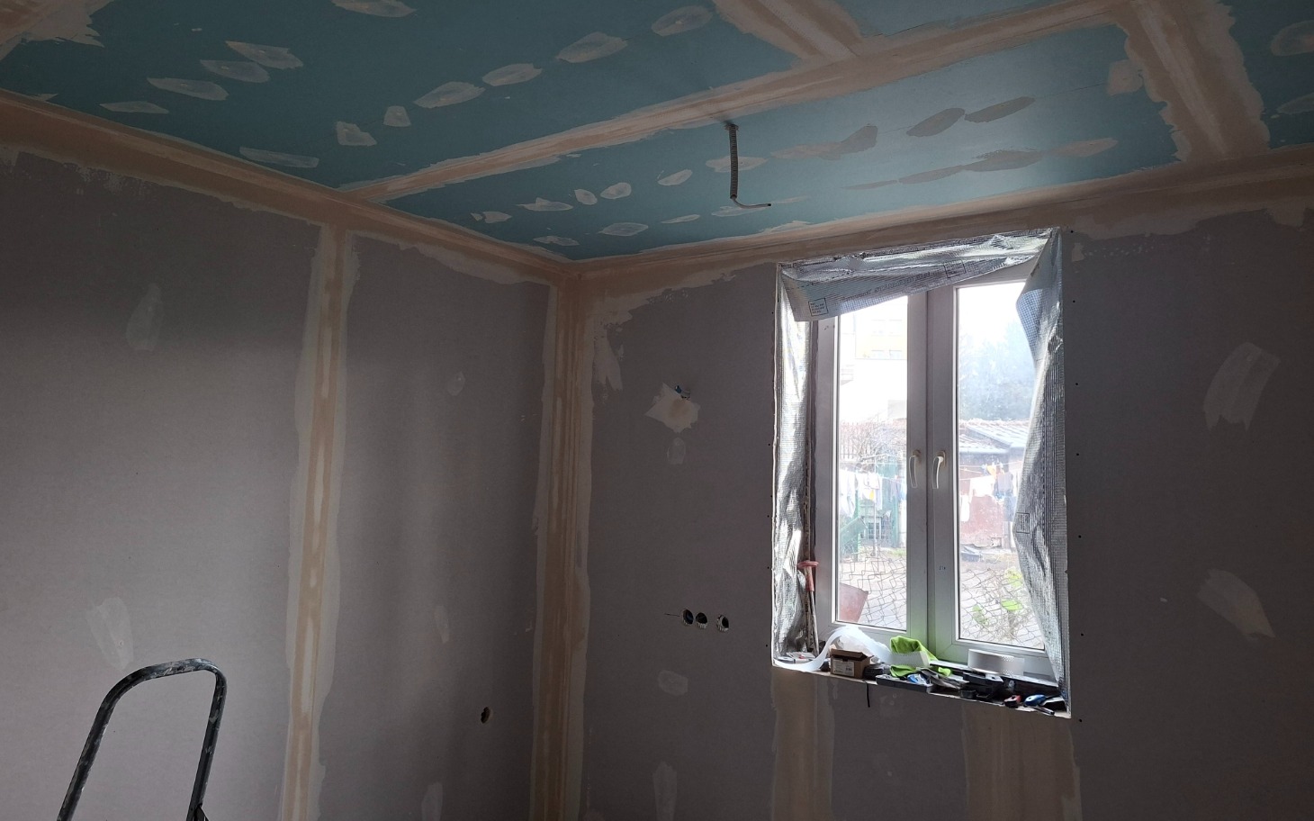 Pokój w trakcie remontu, z nowym sufitem i oknem.