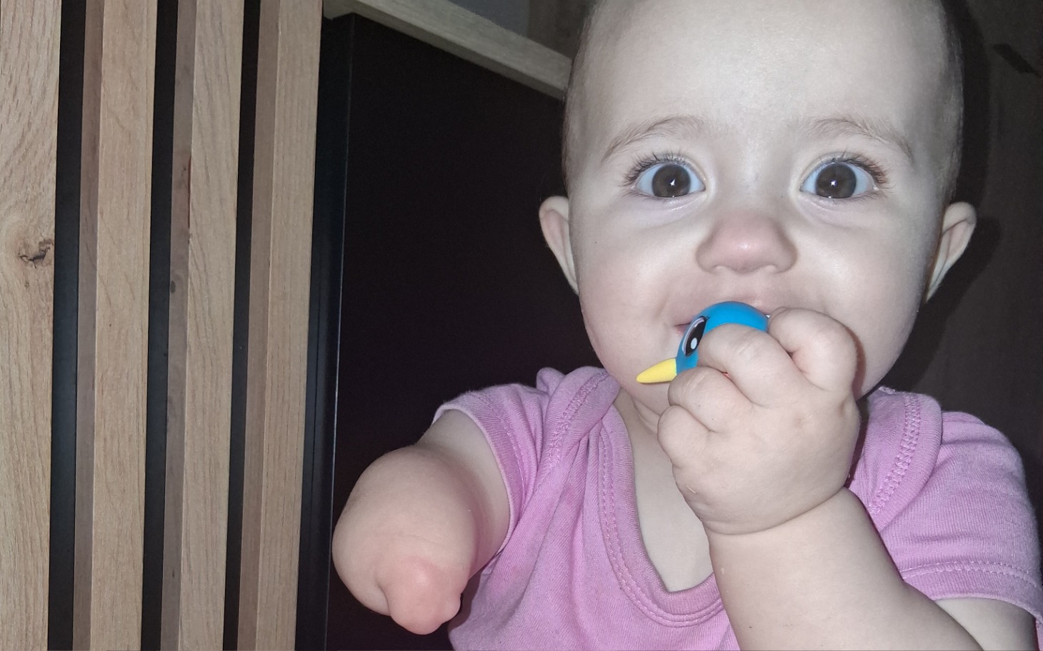 
        Małe dziecko z uśmiechem trzymające zabawkę w ręku.
    