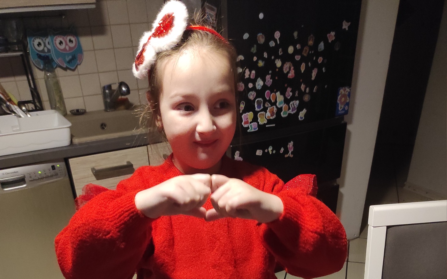 
        Dziewczynka w czerwonym swetrze z ozdobą na głowie.
    