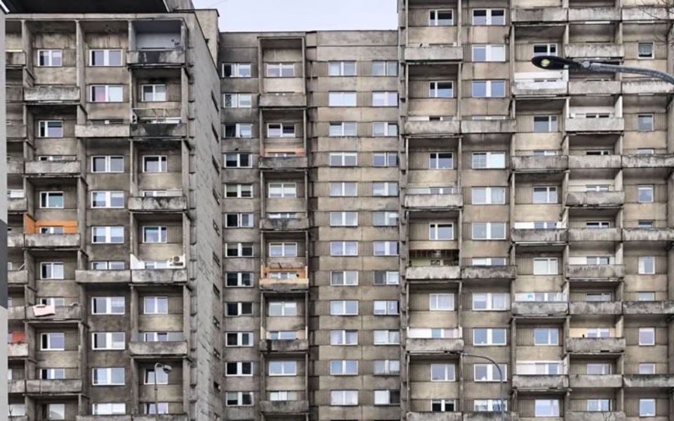 
        Wielopiętrowy blok mieszkalny, szare elewacje.
    