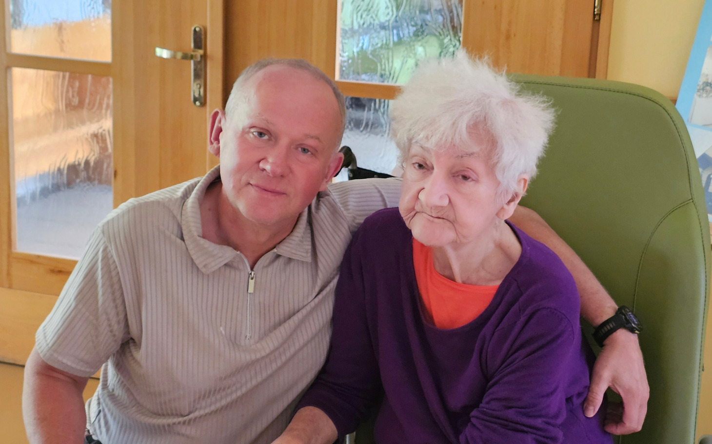 
        Mężczyzna i starsza kobieta siedzący razem w domu.
    