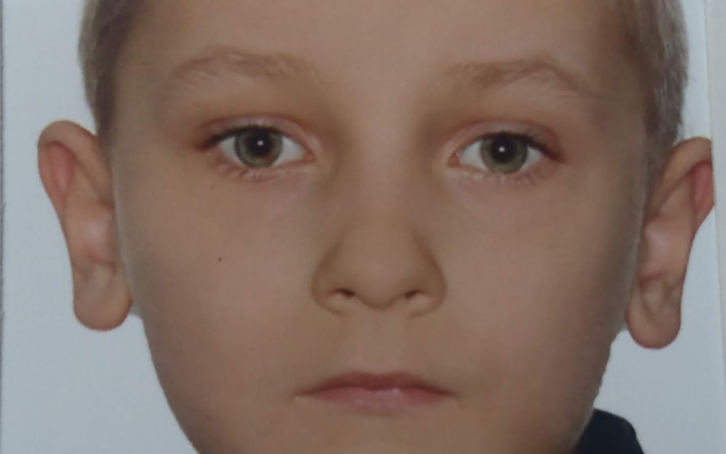 
        Portret chłopca z poważnym wyrazem twarzy.
    