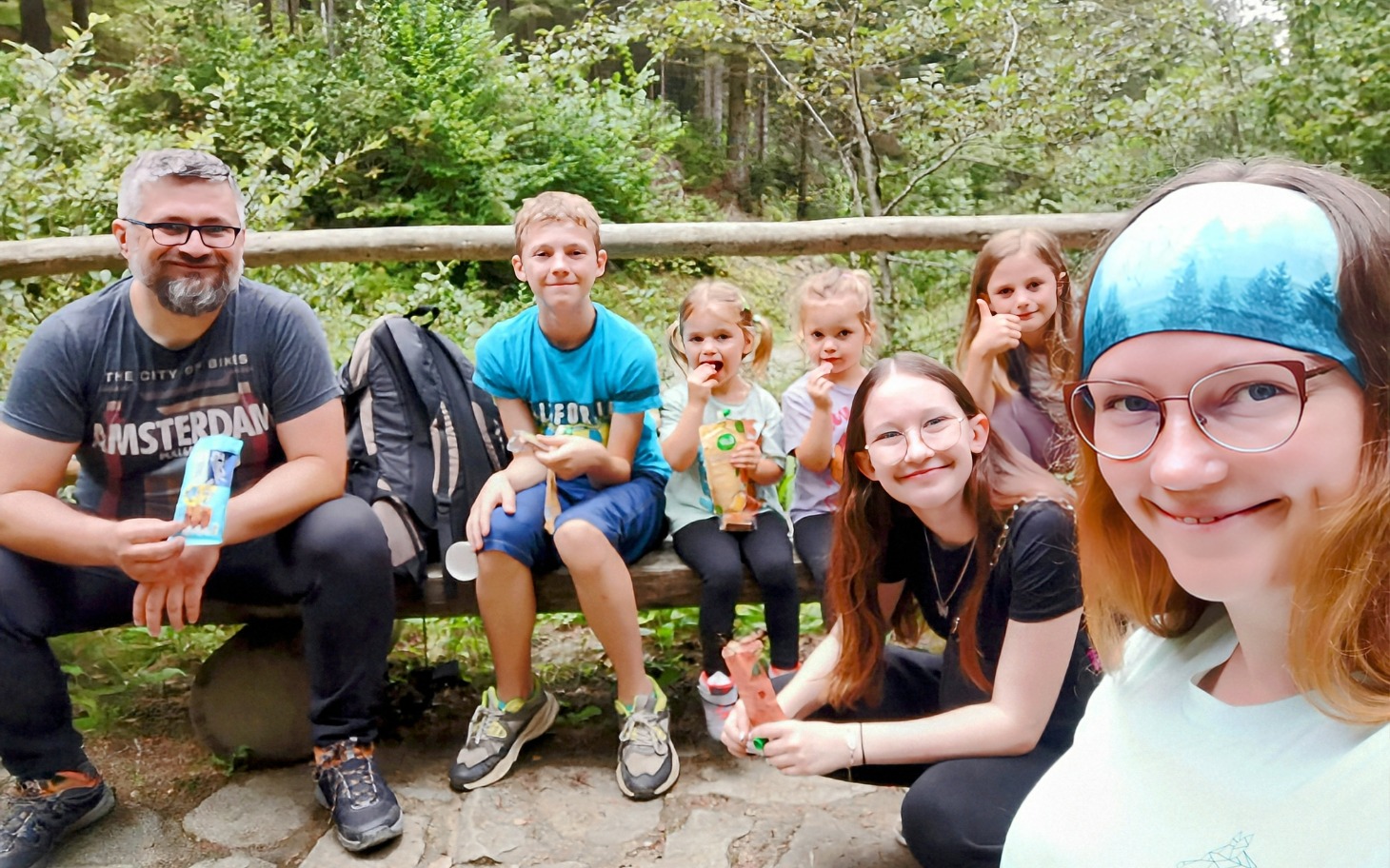 Rodzina z dziećmi na wycieczce w lesie, jedzą lody.