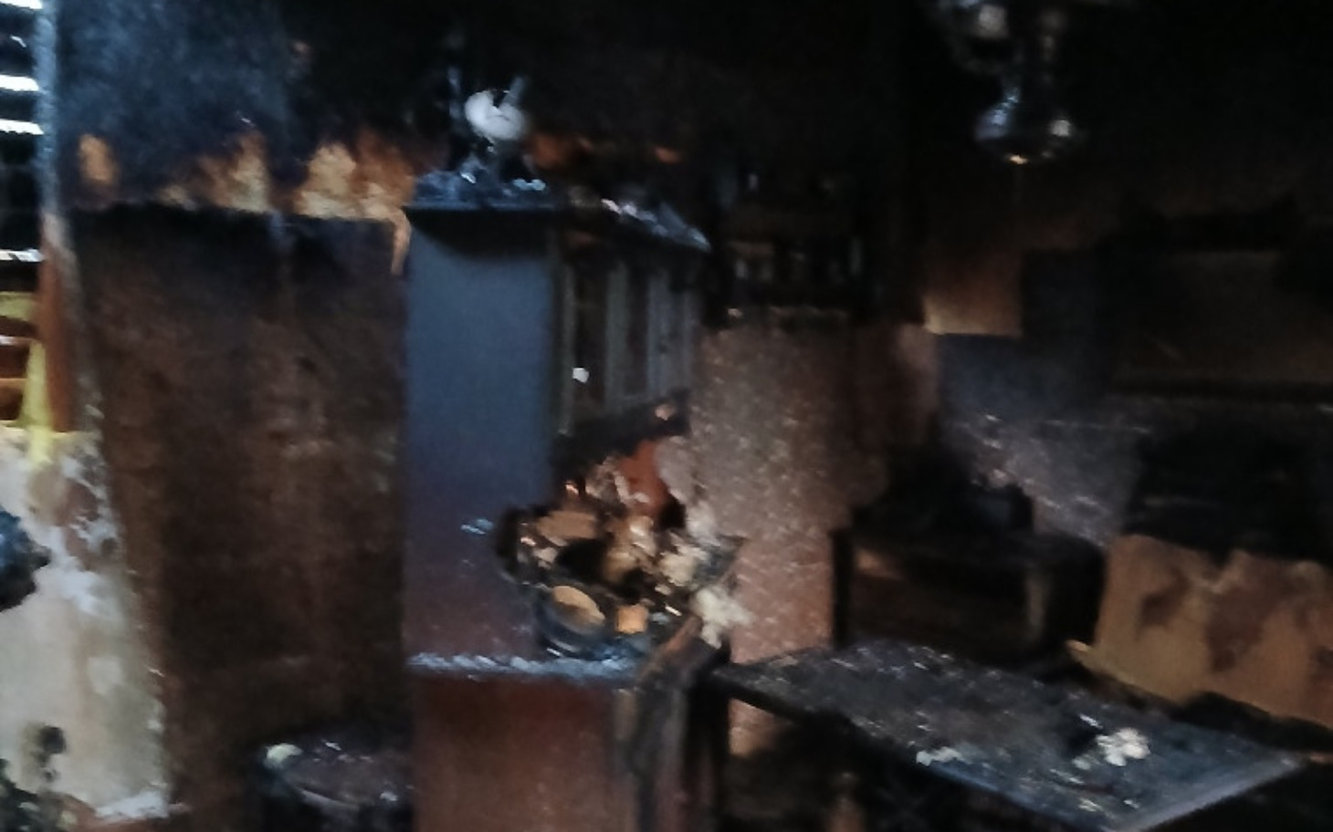 
        Zniszczona kuchnia po pożarze, z popiołem i zniszczeniami.
    