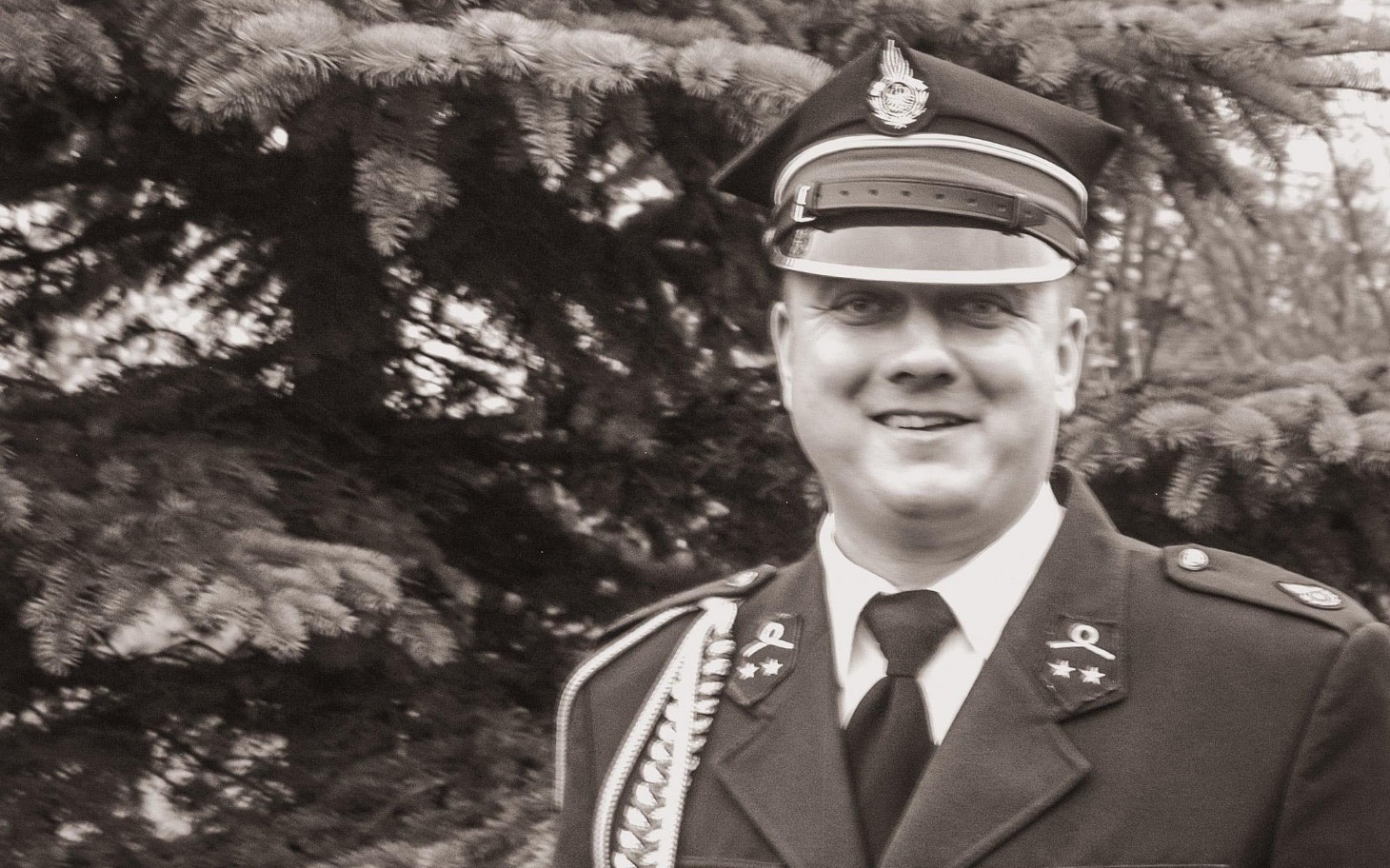 
        Mężczyzna w mundurze, uśmiechający się do kamery.
    