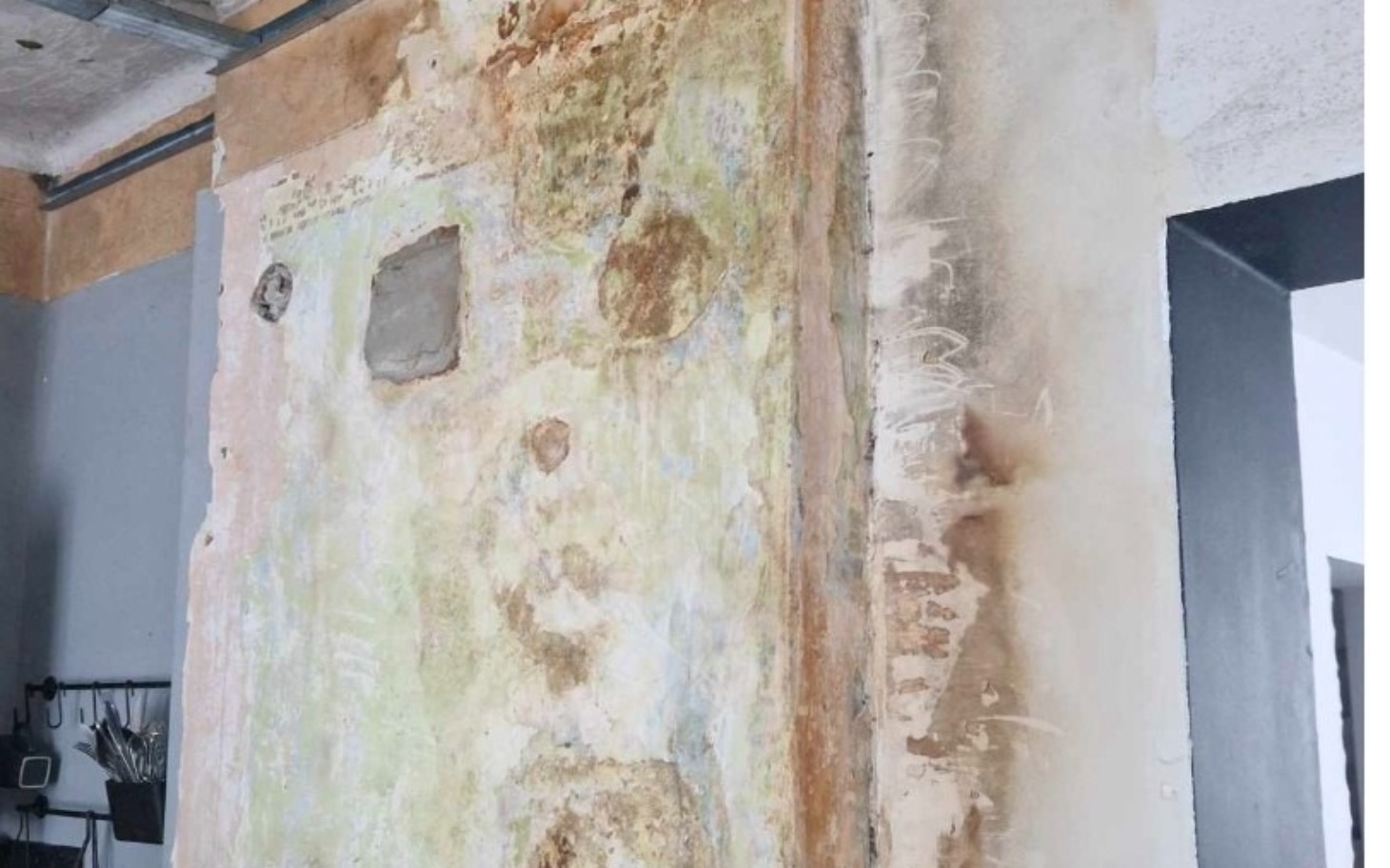 
        Ściana z odchodzącą farbą i uszkodzeniami.
    