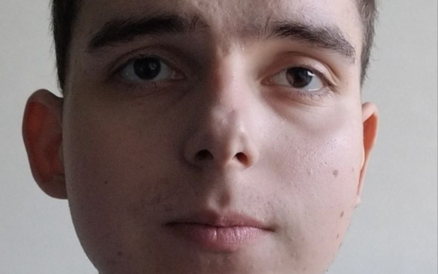 
        Młody mężczyzna z poważnym wyrazem twarzy.
    