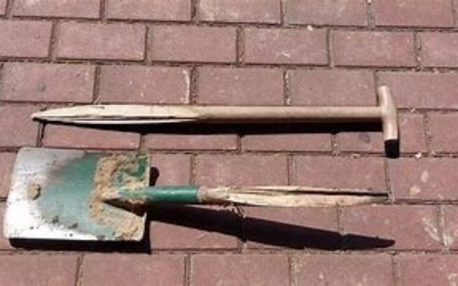 
        Narzędzia ogrodnicze leżące na bruku, w używanym stanie.
    