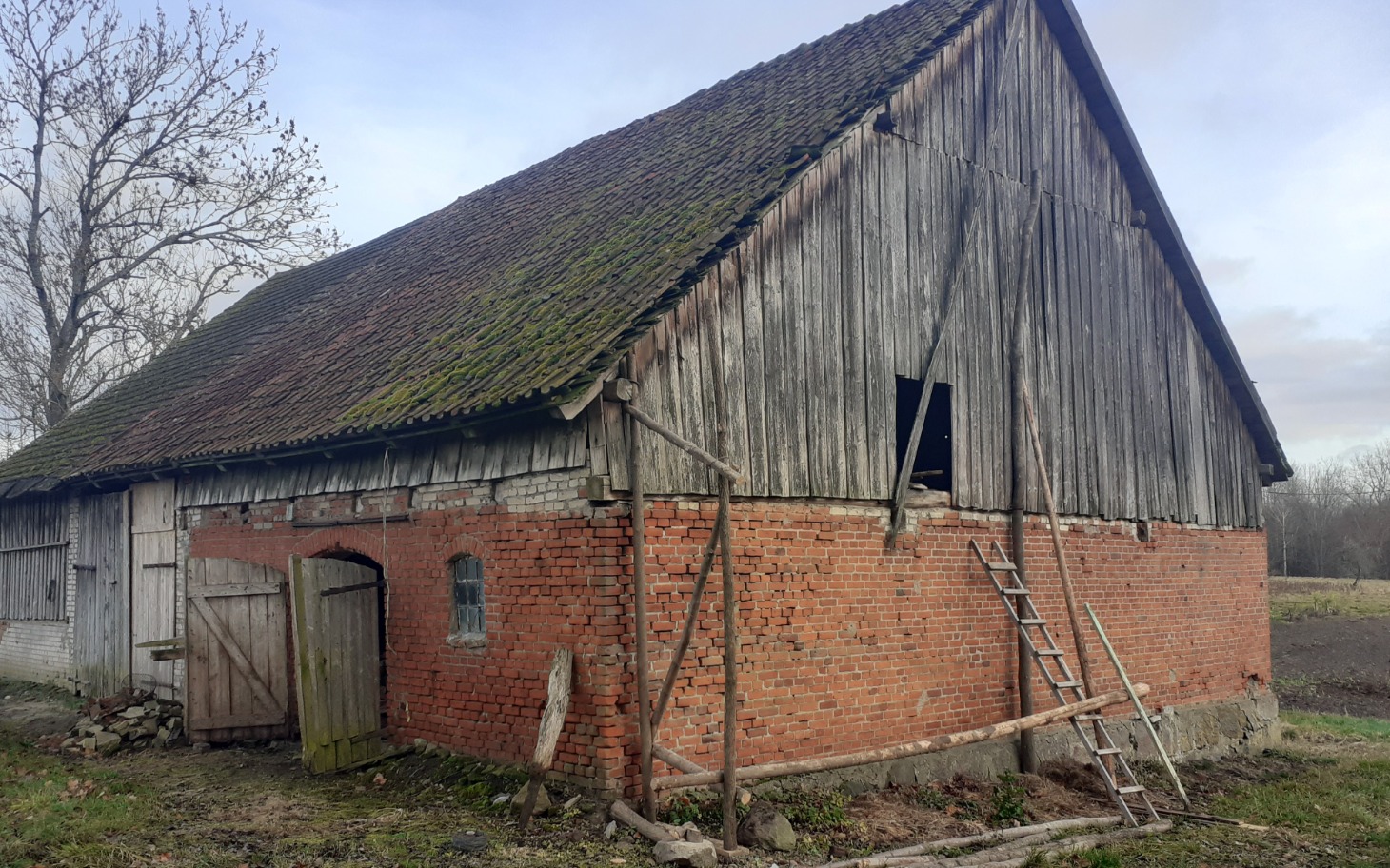 
        Stara stodoła z cegły, z widocznymi uszkodzeniami.
    
