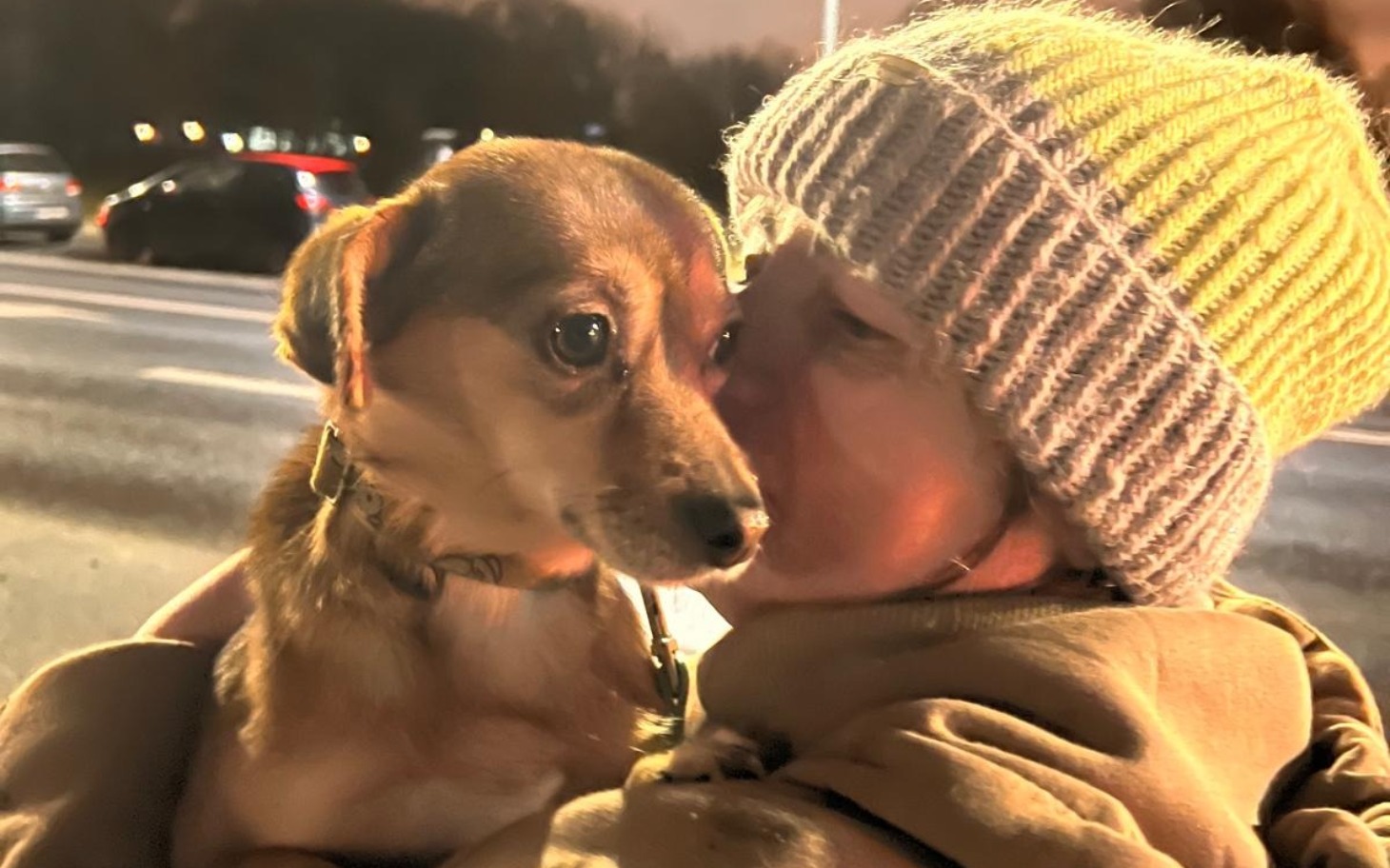 
        Kobieta całująca psa w ciepłej czapce.
    