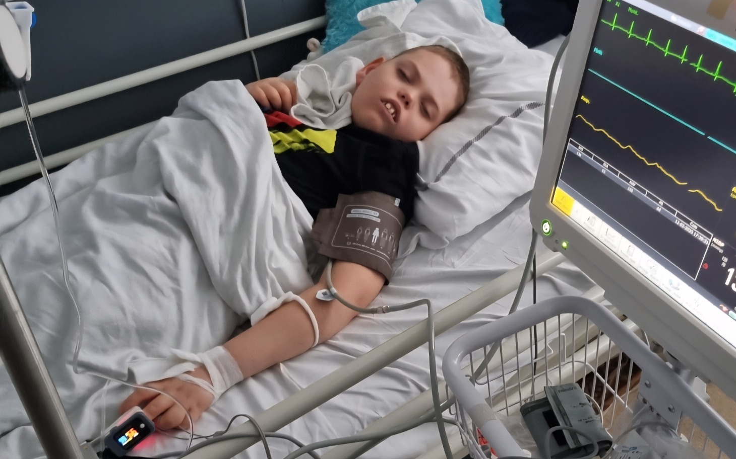 
        Chłopiec leży w szpitalnym łóżku, podłączony do monitorów.
    