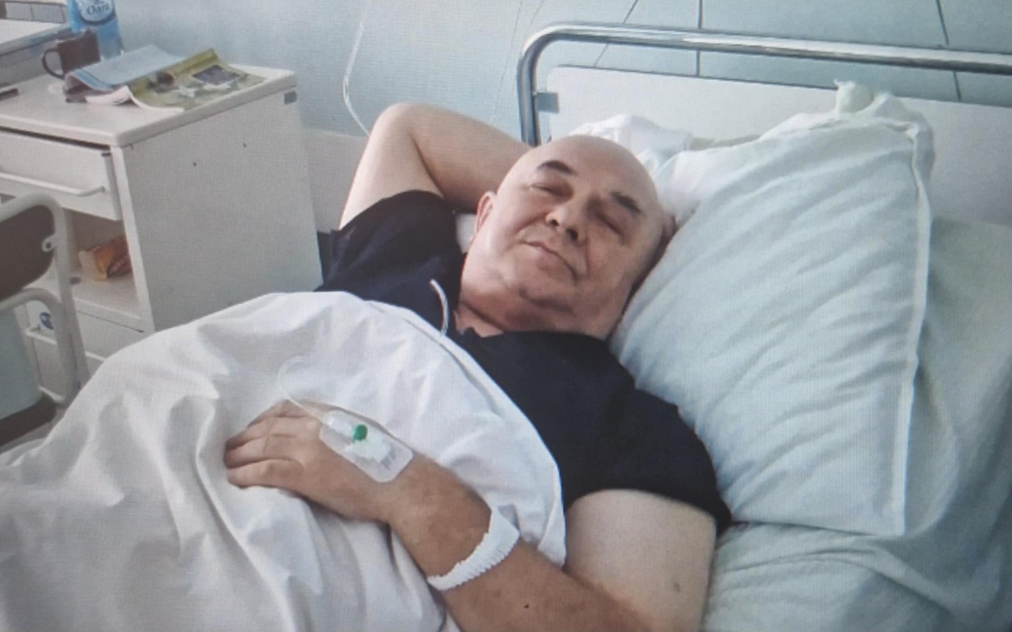 
        Mężczyzna leżący w szpitalnym łóżku, zrelaksowany i spokojny.
    