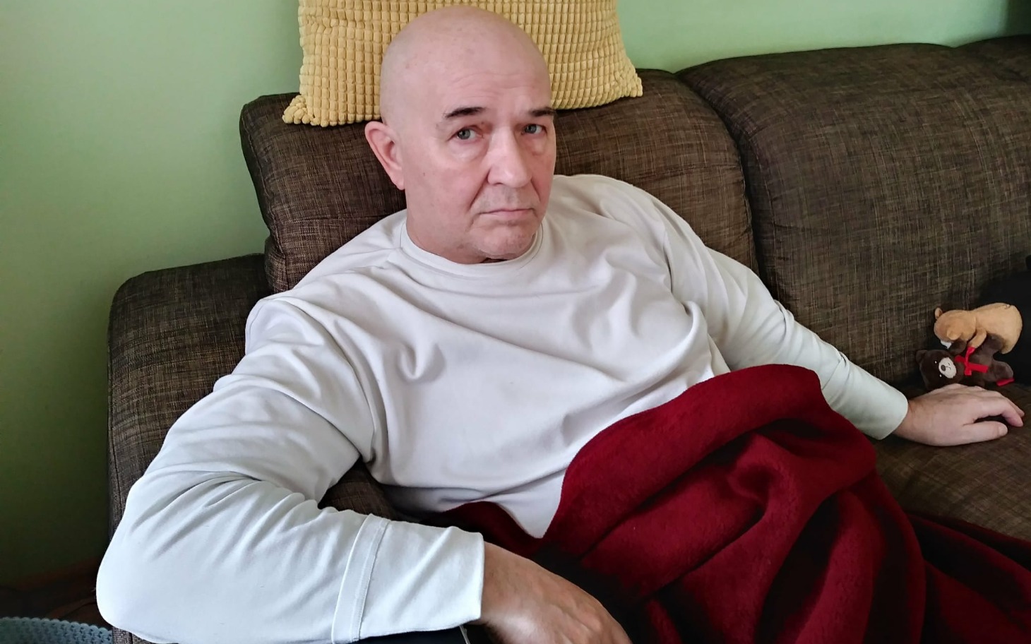 
        Mężczyzna odpoczywający na kanapie z kocem.
    