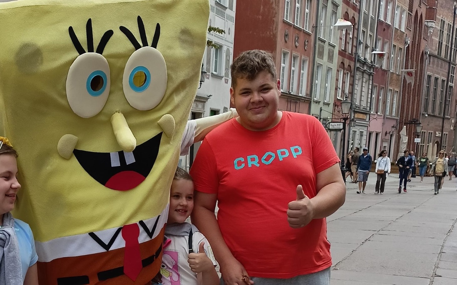 
        Chłopiec z postacią SpongeBoba, oboje uśmiechnięci na ulicy.
    