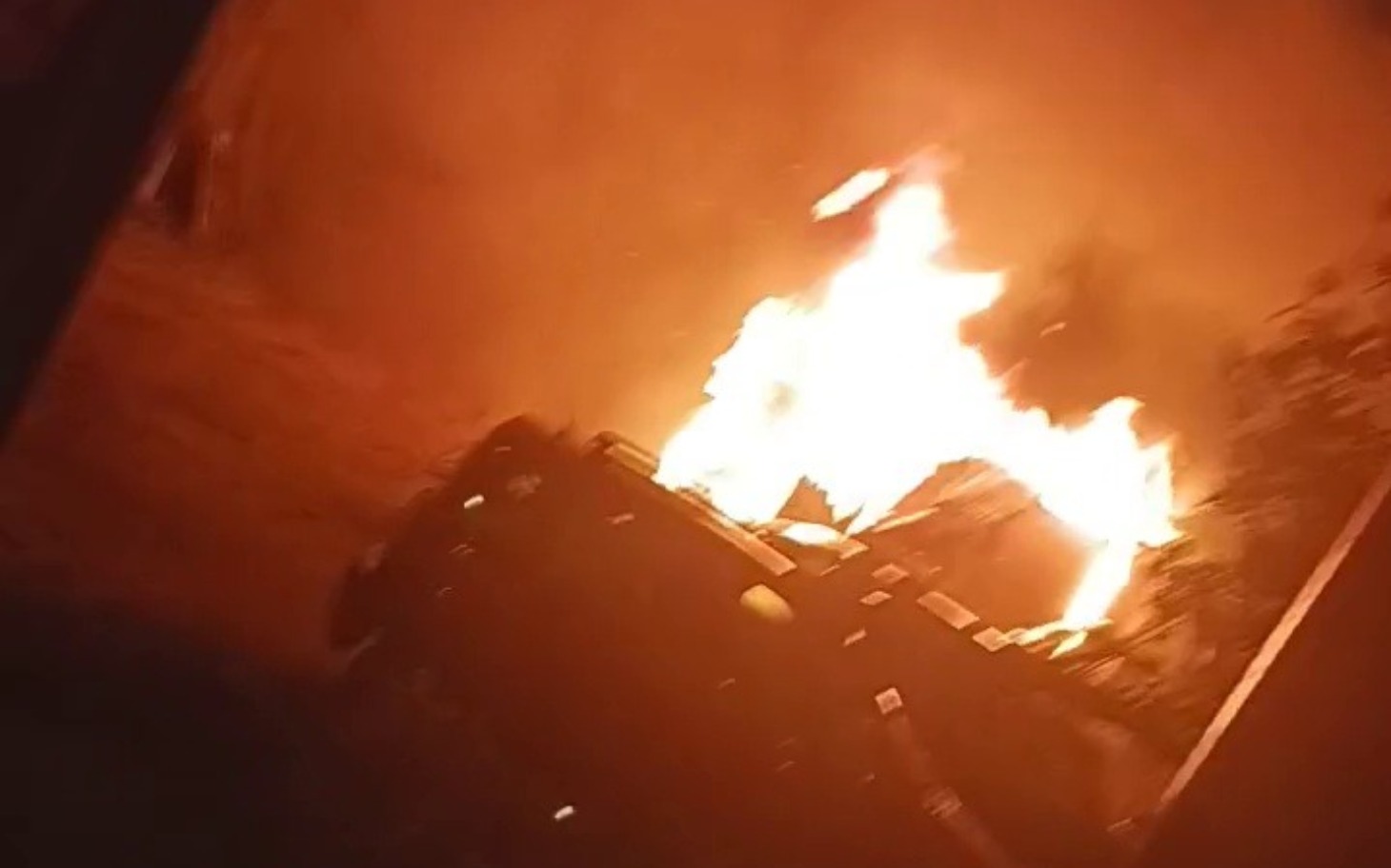 
        Pojazd w płomieniach, otoczony dymem i ogniem, w dramatycznej scenerii.
    