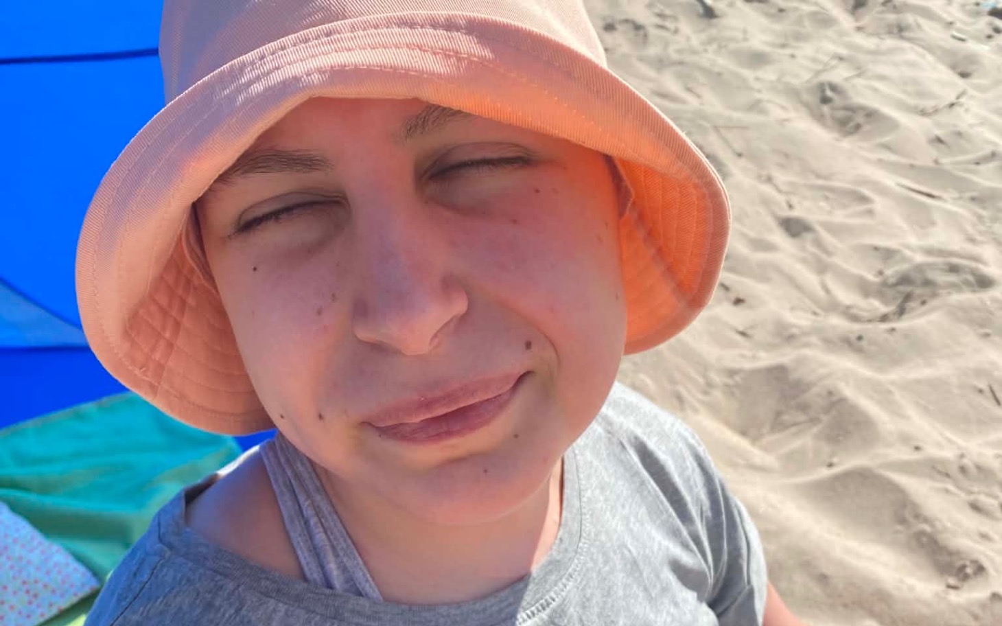 
        Dziecko w piżamie leżące na plażowym kocyku w słoneczny dzień
    