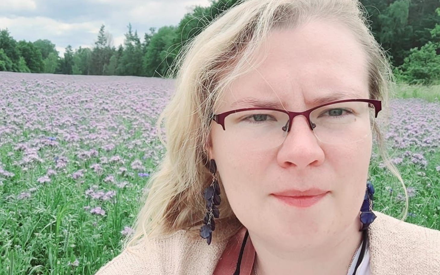 
        Kobieta na tle pola pełnego fioletowych kwiatów.
    