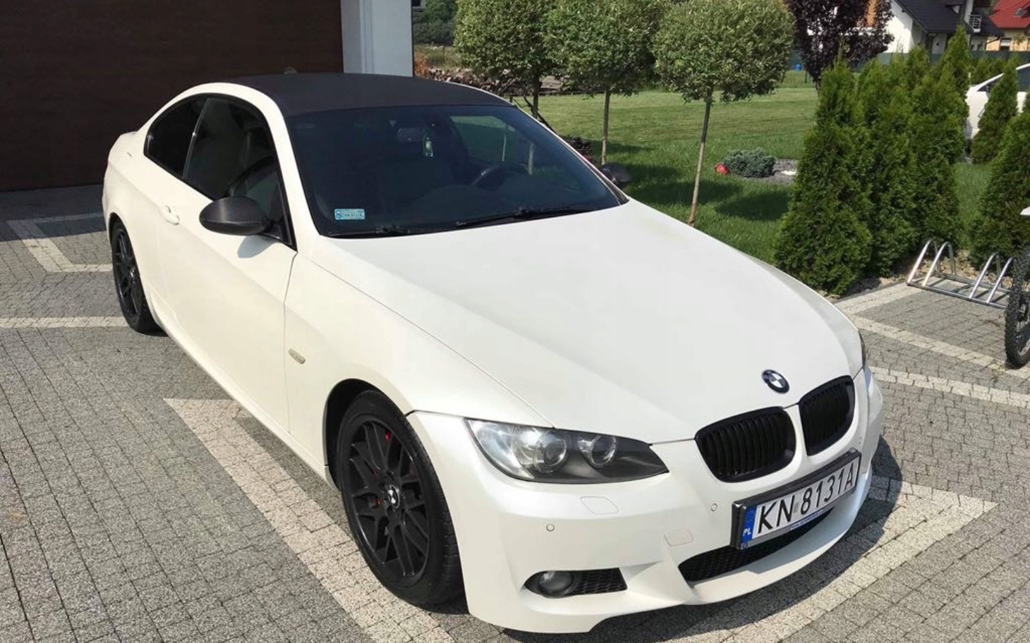 
        Biały samochód marki BMW zaparkowany na podjeździe.
    