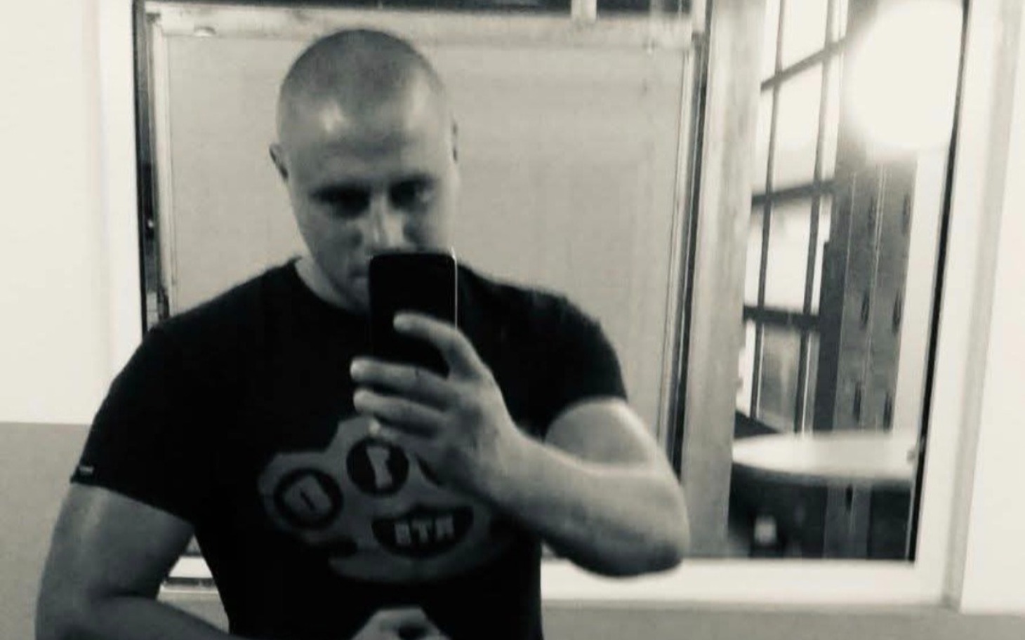 
        Mężczyzna robiący selfie w lustrze na siłowni.
    