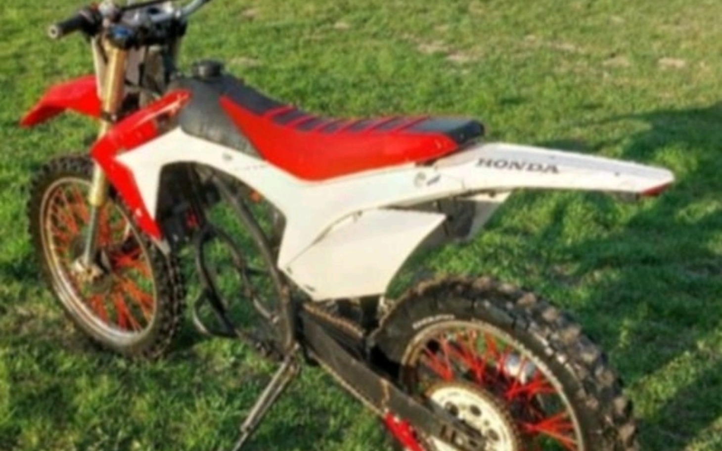 
        Motocykl terenowy na zielonej trawie.
    