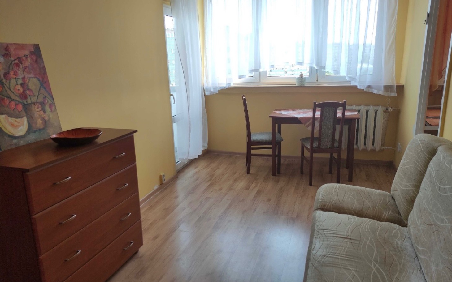 
        Przytulne wnętrze mieszkania z jasnymi ścianami i drewnianą podłogą.
    