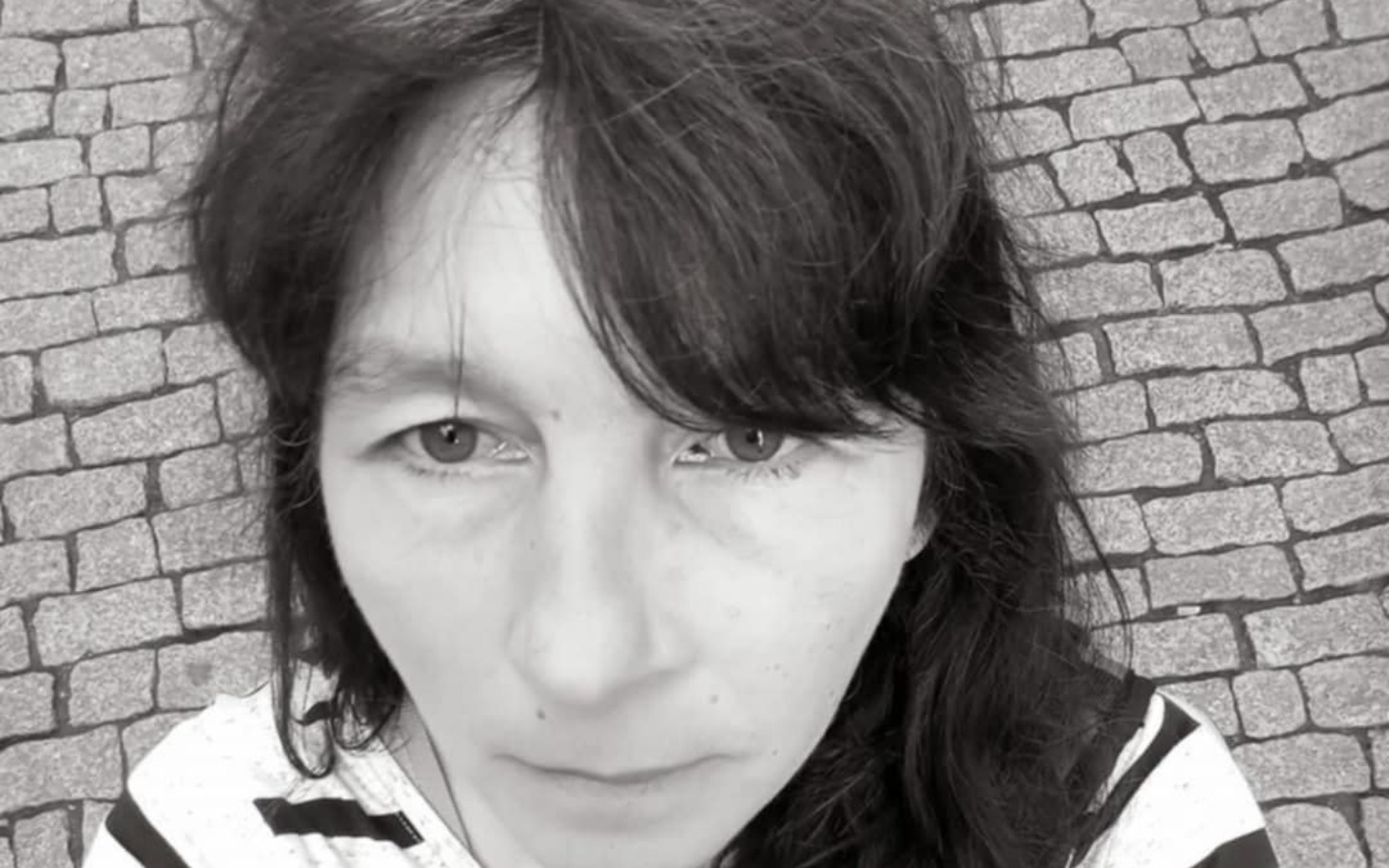 
        Portret kobiety na brukowanej ulicy.
    