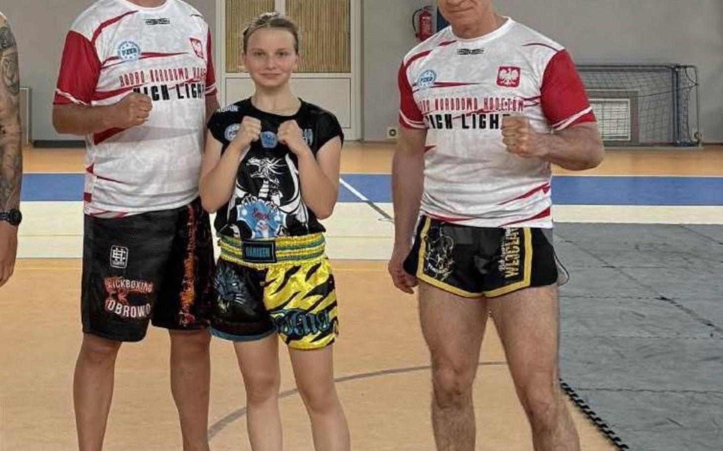 
        Trenerzy i młoda zawodniczka w strojach sportowych na treningu.
    