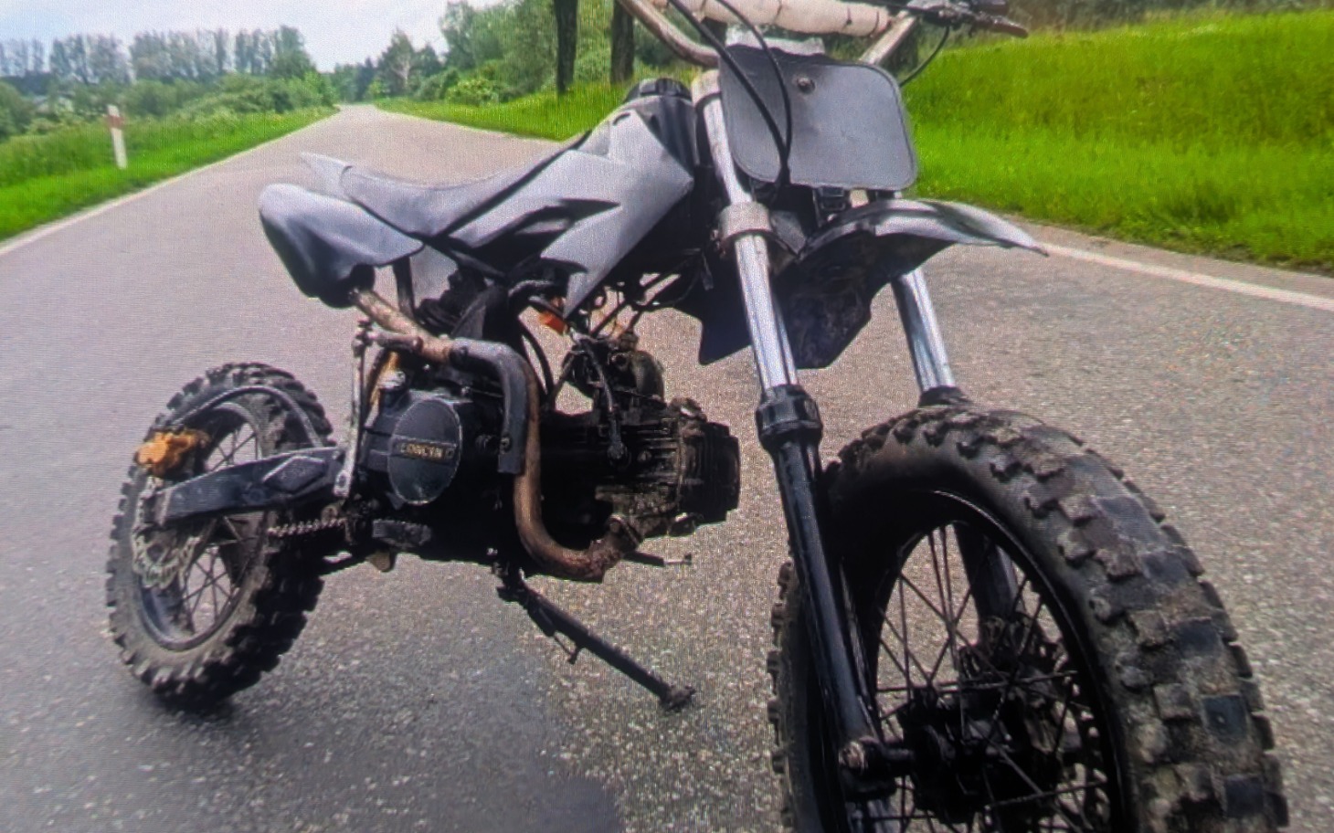 
        Motocykl terenowy na drodze, z widocznymi oponami.
    