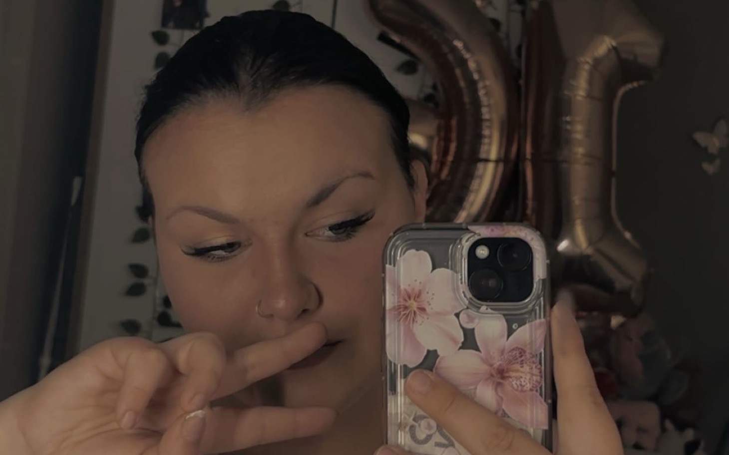 
        Młoda kobieta robiąca selfie z kwiatowym etui na telefon.
    