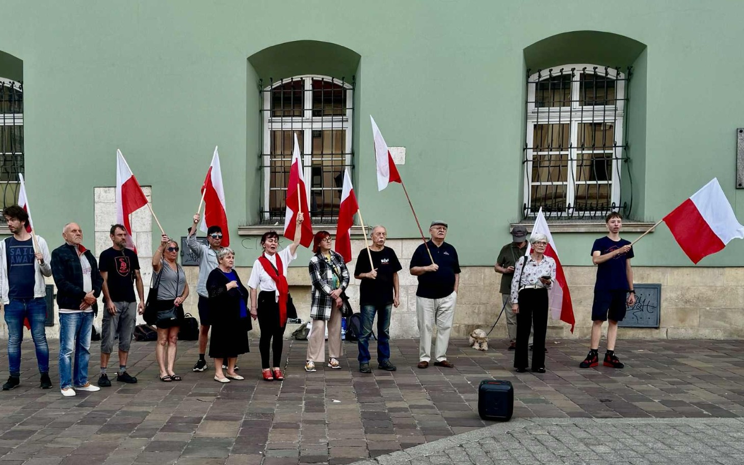 
        Grupa ludzi z flagami, protestująca na ulicy.
    