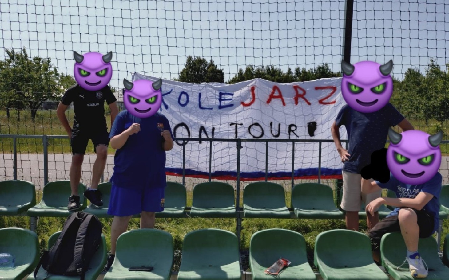 
        Grupa kibiców z transparentem, wesoła atmosfera na trybunach.
    