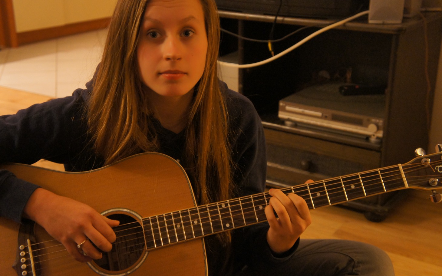 
        Dziewczyna grająca na gitarze, skupiona na muzyce.
    