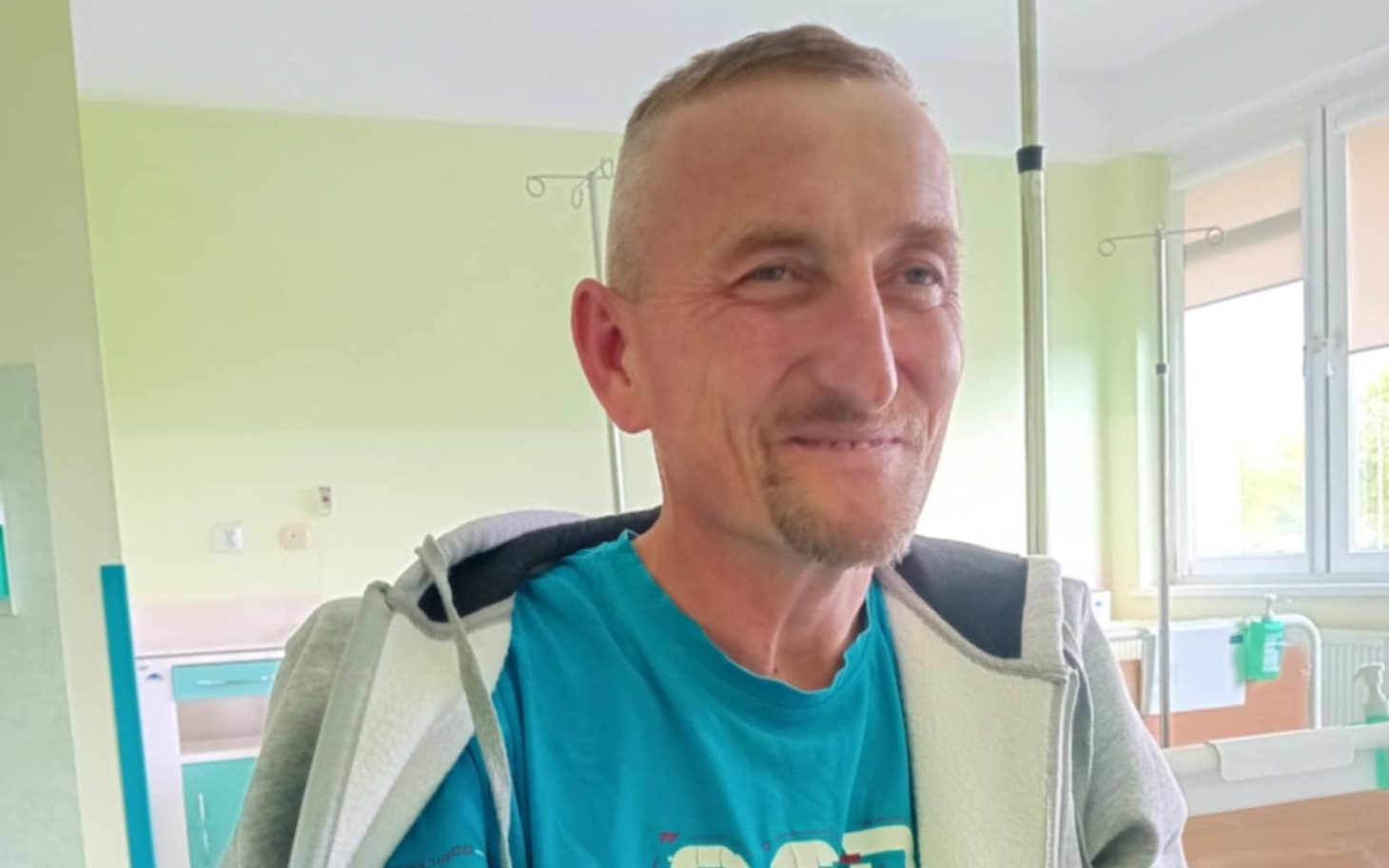 
        Mężczyzna w szpitalu, uśmiechający się, w niebieskiej koszulce.
    
