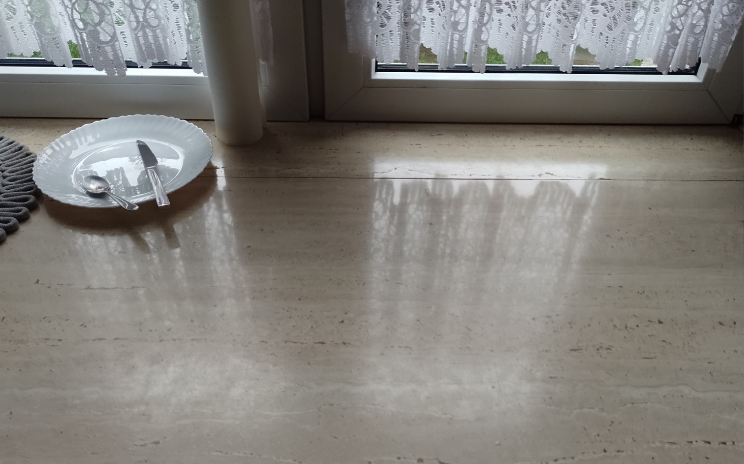 
        Pusty stół z talerzem i sztućcami przy oknie.
    