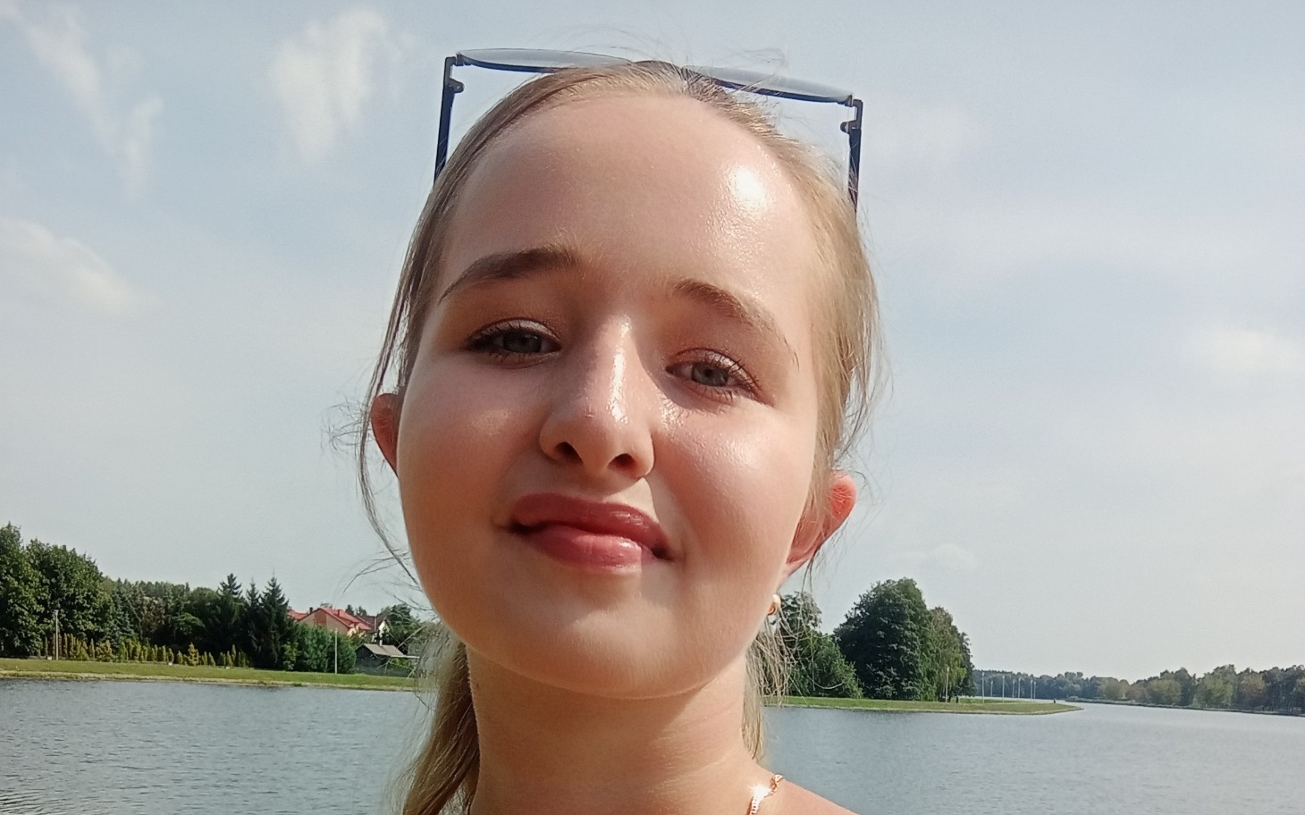 
        Młoda dziewczyna uśmiechająca się nad wodą.
    