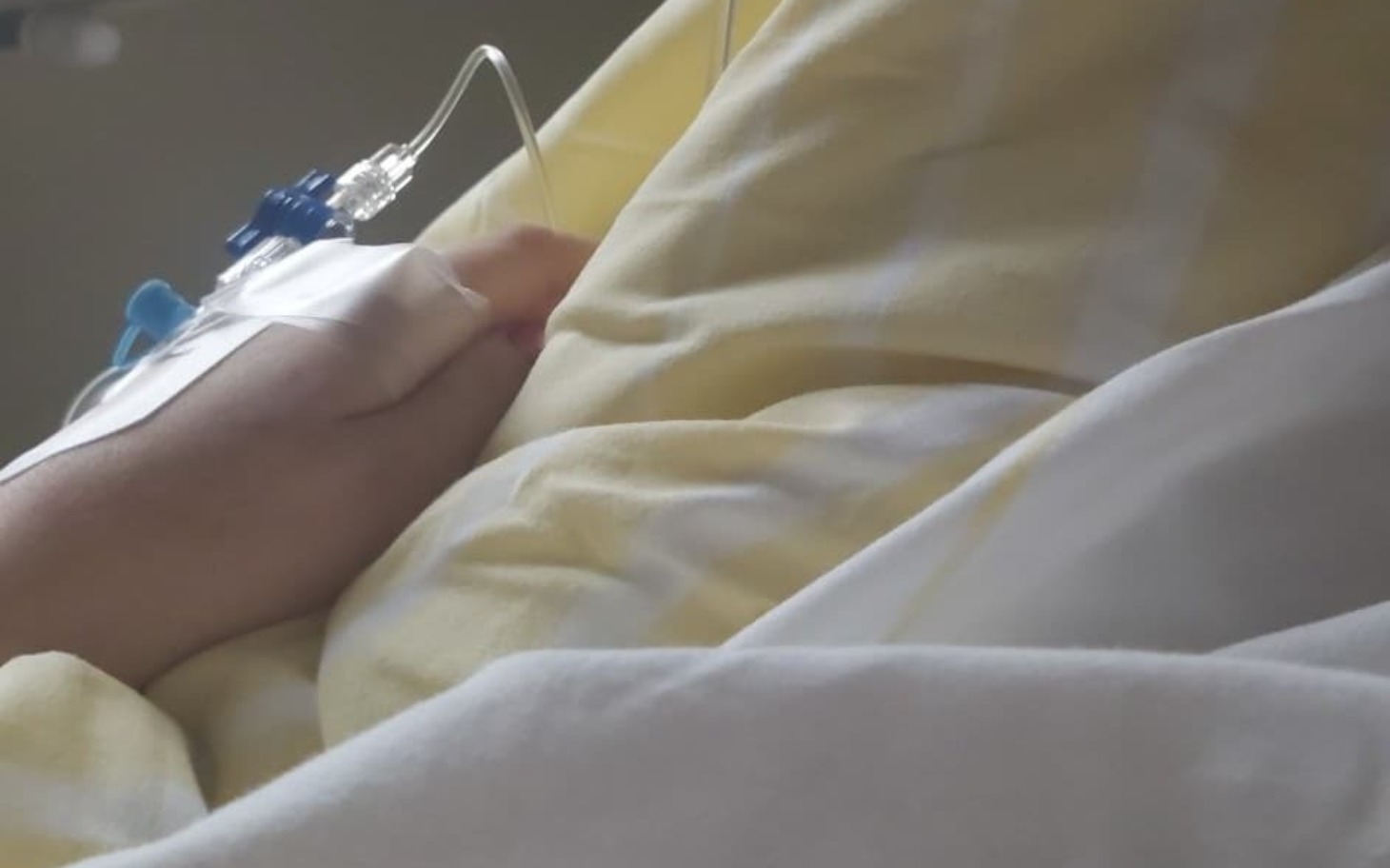 
        Ręka pacjenta z kroplówką, leżąca na pościeli.
    