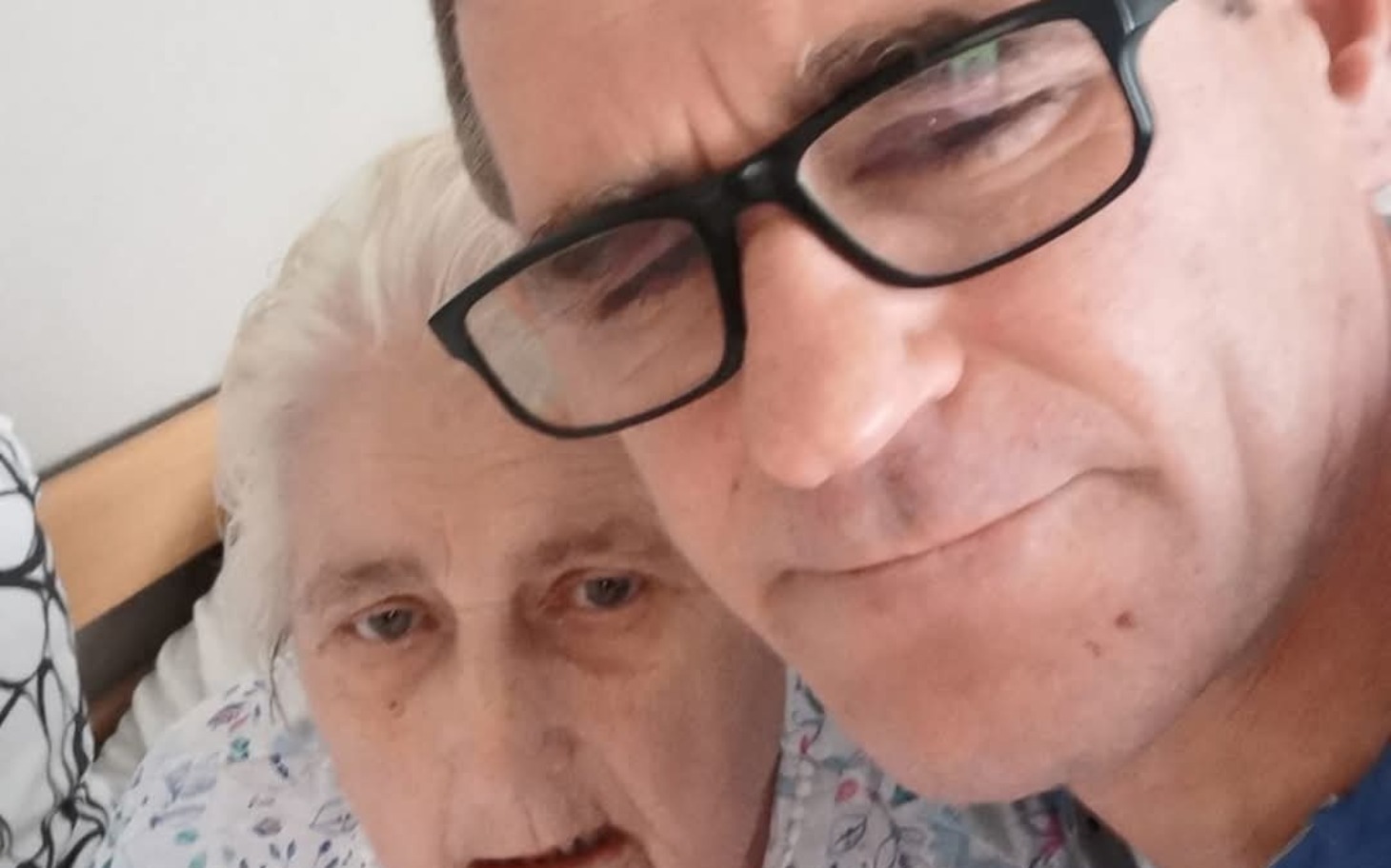 
        Osoba z okularami selfie z starszą kobietą w łóżku.
    