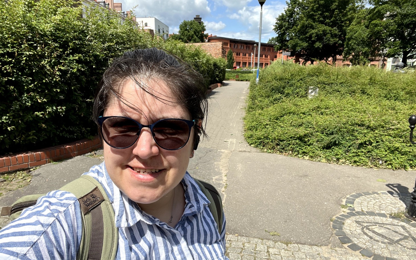 
        Osoba na spacerze w parku, otoczona zielenią i architekturą.
    