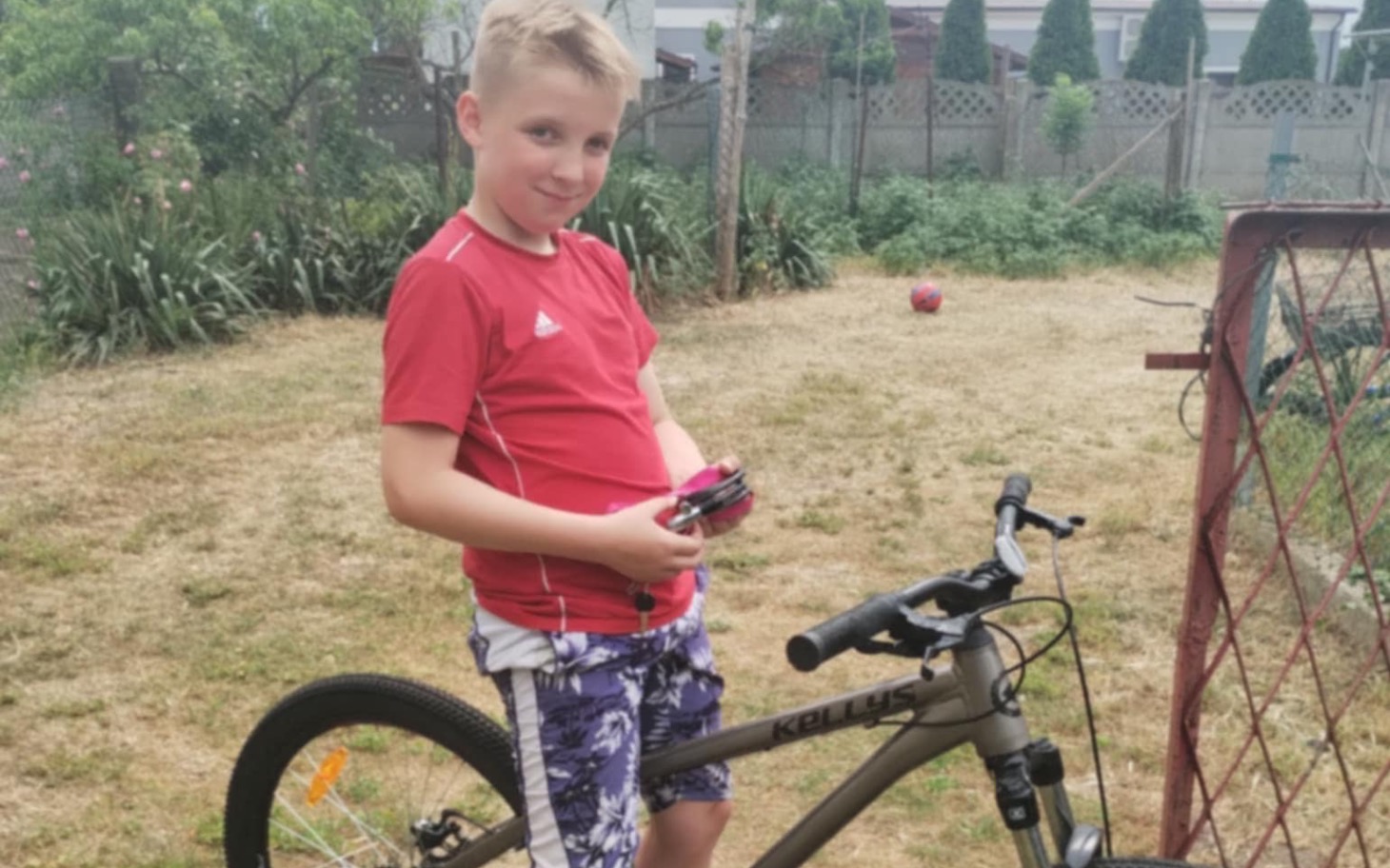
        Chłopiec z pilotem stoi obok roweru.
    