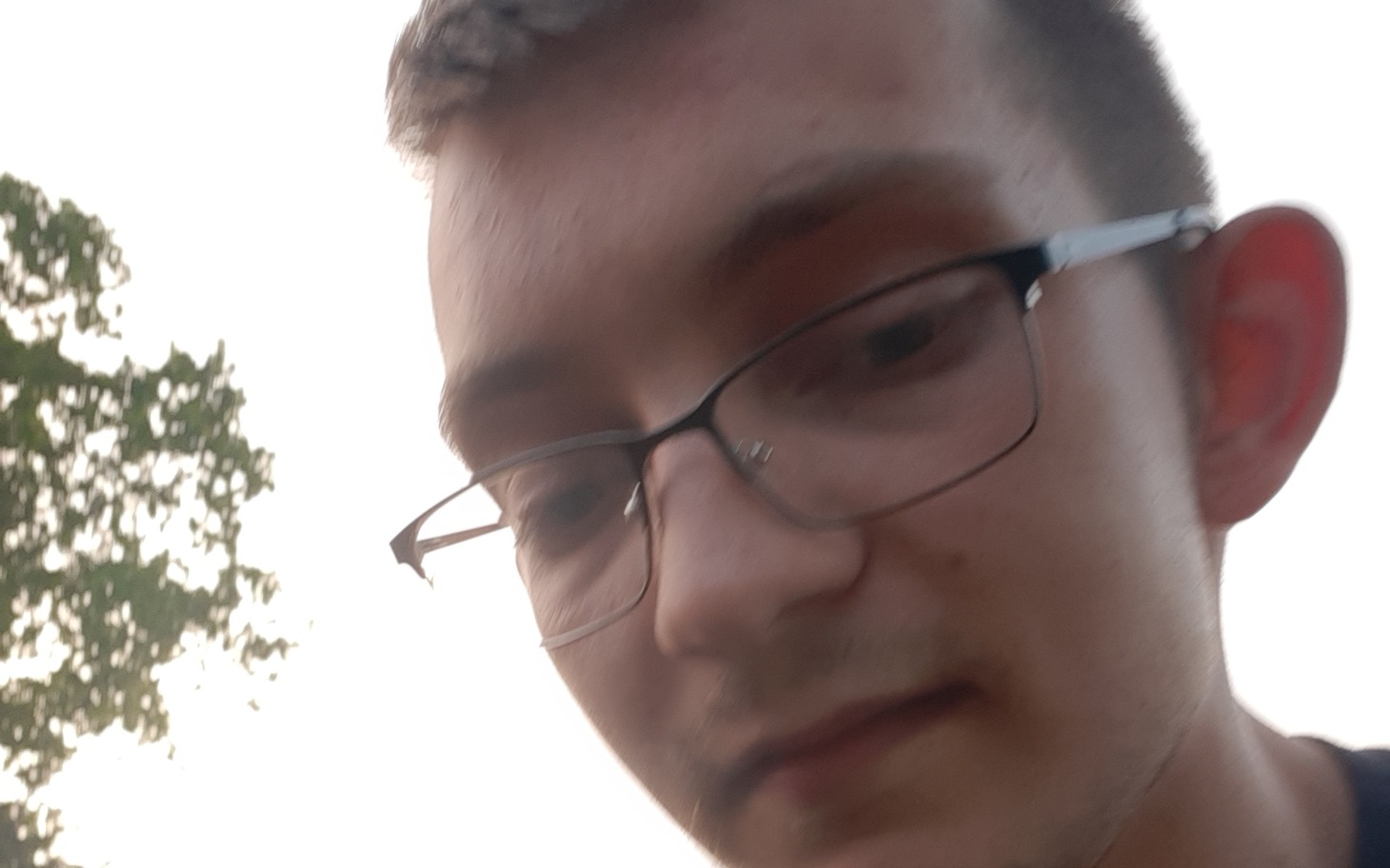 
        Młody mężczyzna w okularach, selfie w plenerze.
    