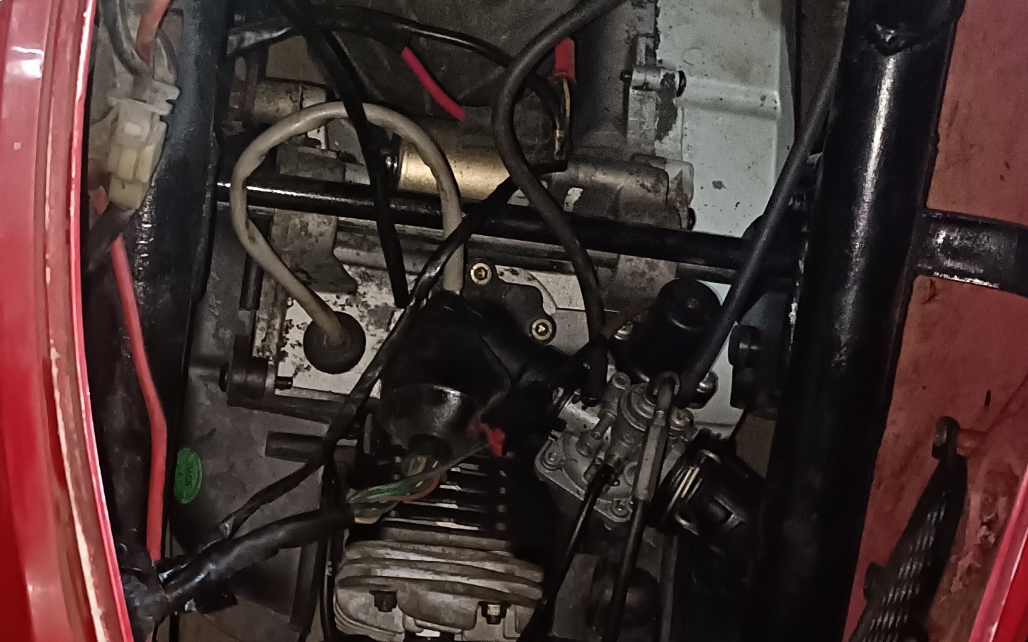
        Widok na silnik motocykla z przewodami i elementami mechanicznymi.
    