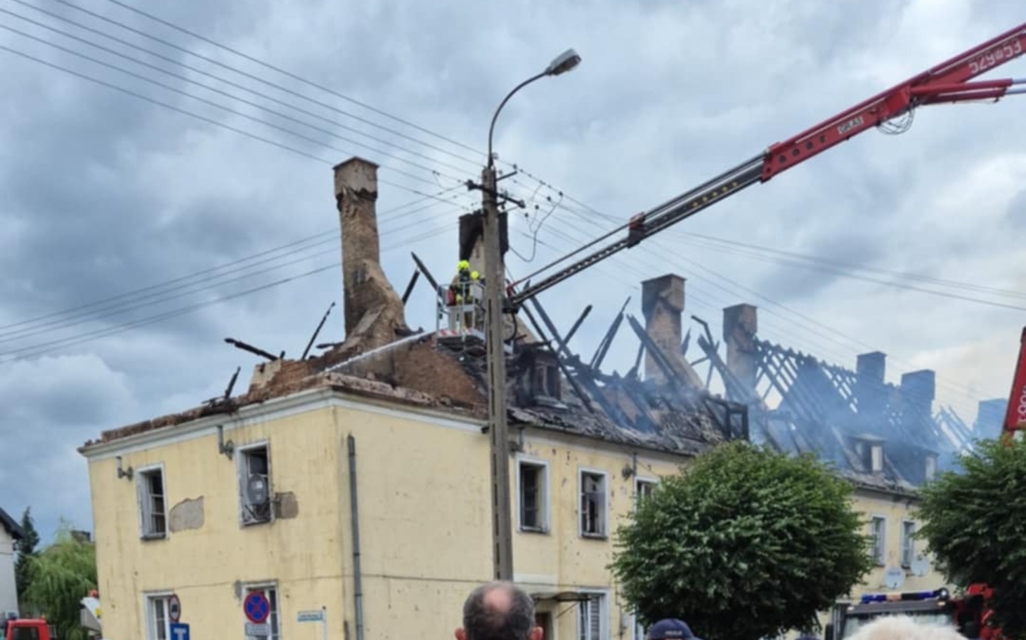 
        Zniszczony budynek po pożarze, z dymem unoszącym się w powietrzu.
    