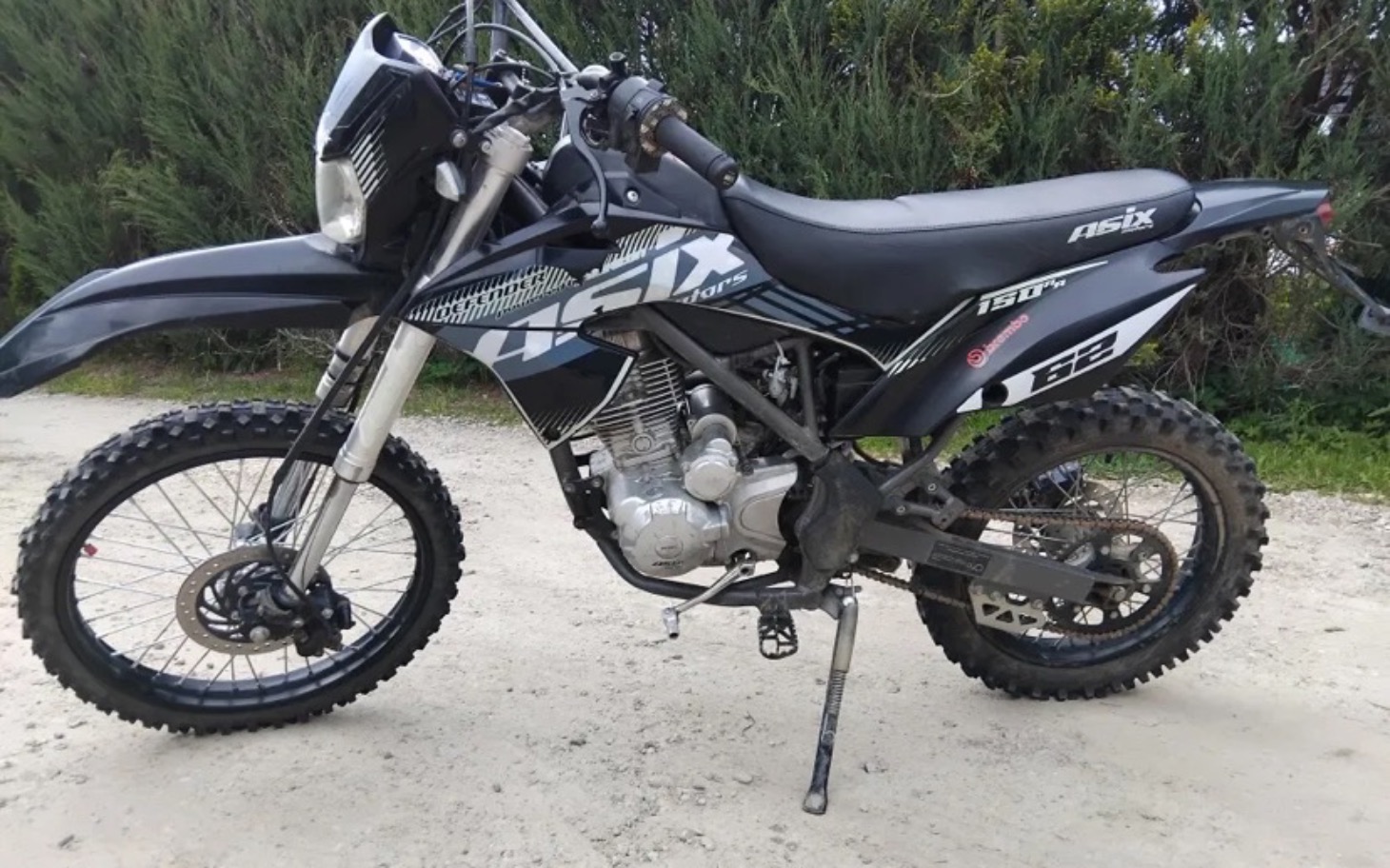 
        Motocykl terenowy zaparkowany na drodze.
    