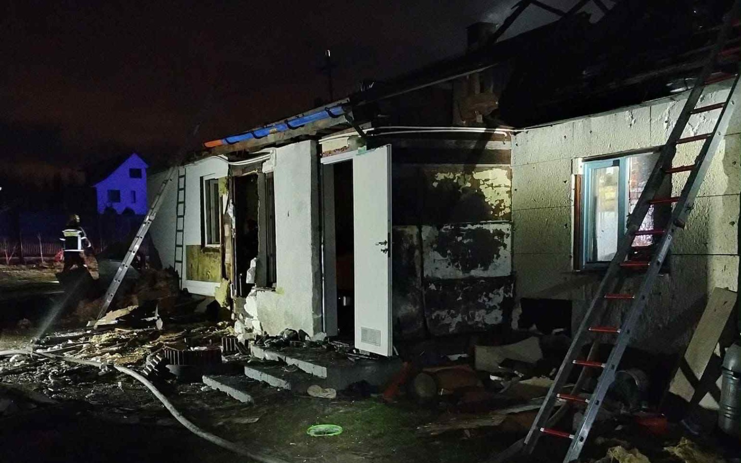
        Zniszczony dom po pożarze, widok z zewnątrz.
    