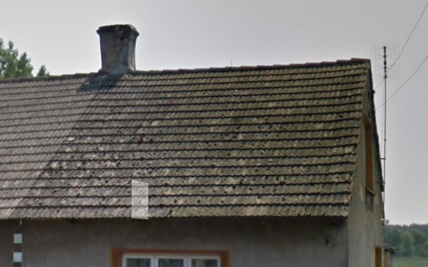 
        Widok na dach domu z widocznymi oznakami zużycia.
    