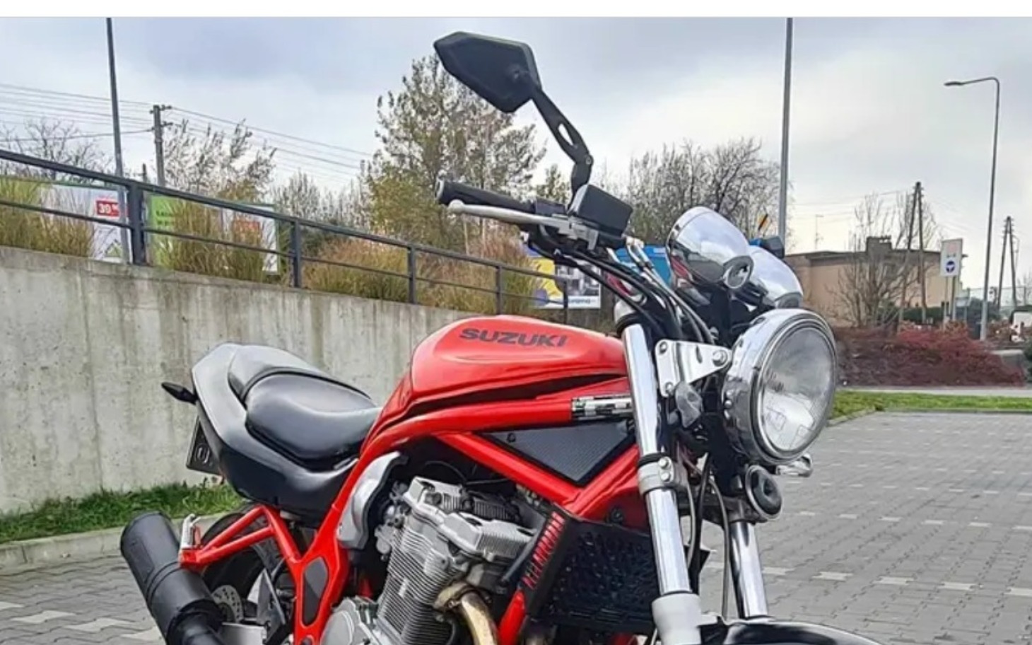 
        Motocykl Suzuki zaparkowany na chodniku.
    