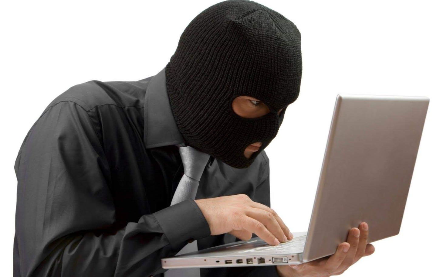 
        Mężczyzna w kominiarce pracujący na laptopie.
    