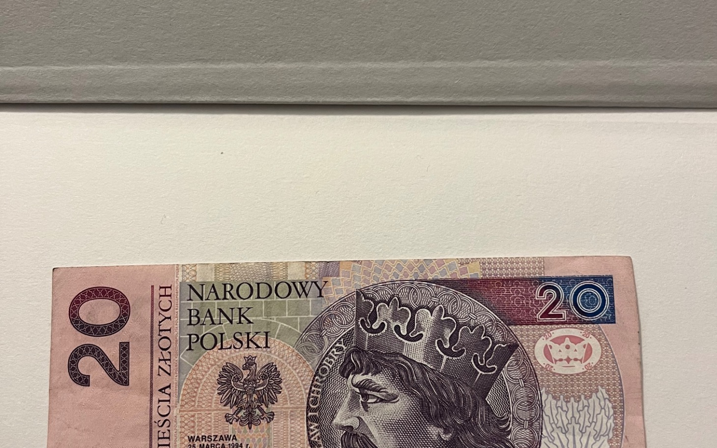 
        Banknot 20 złotych z wizerunkiem króla na tle polskiego godła.
    