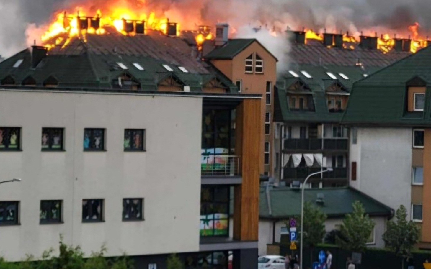 
        Widok na płonący dach budynku, dym unoszący się w powietrzu.
    